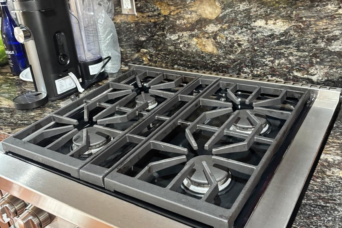 Spotless five-burner gas cooktop set into a polished granite countertop